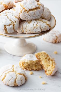 powdered sugar cookies on a cake stand with one cut in half and the rest partially eaten