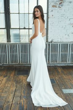 a woman in a white dress standing on a wooden floor with her back to the camera