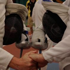 two people in fencing gear hold their hands together