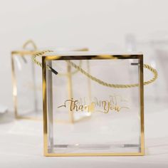 two clear boxes with gold lettering on the front and bottom, one has a rope wrapped around it