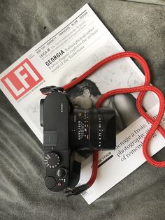 a camera sitting on top of a bed next to a red cord and paper with an ef logo