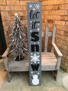 a wooden sign that says let it snow next to a bench with a christmas tree