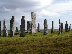 a group of large rocks sitting on top of a lush green field under a cloudy sky