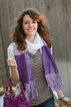 a woman carrying a purple purse and wearing a scarf over her shoulders, smiling at the camera