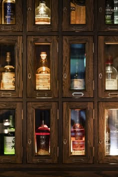 many bottles of different types and sizes are on display in a wooden case with glass doors