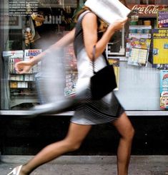 a woman is walking down the street with a book in her hand