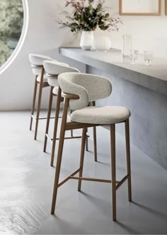 four bar stools are lined up in front of a counter with flowers on it