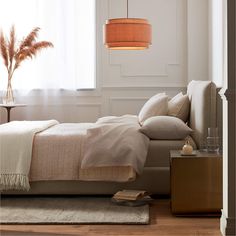 a bed sitting next to a window with a lamp hanging above it and a rug on the floor