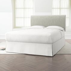 a white bed sitting in a bedroom on top of a hard wood floor