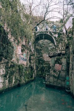 a river running through a stone bridge surrounded by trees