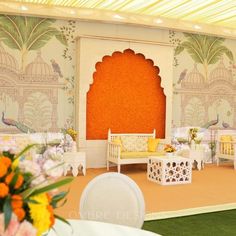 an elaborately decorated room with white furniture and orange walls, flowers in vases on the floor