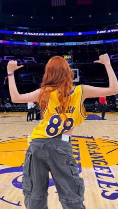 a woman standing on top of a basketball court with her arms up in the air