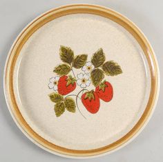 a plate with strawberries and flowers painted on the side, sitting on a black surface