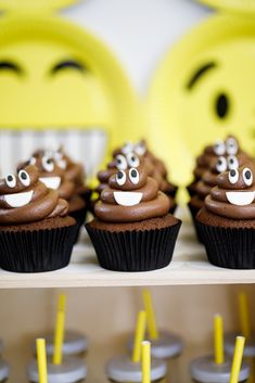 cupcakes with chocolate frosting and googly eyes are on a shelf next to yellow straws