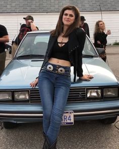 a woman standing next to a blue car