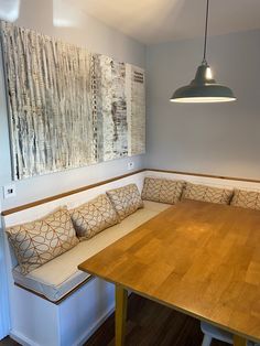 a wooden table sitting next to a white bench with pillows on it's back