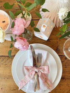 the table is set with pink flowers and silverware