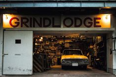 an old car is parked in front of the grindlodge garage door with lights on