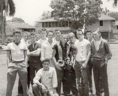 a group of young men standing next to each other in front of a tree and building