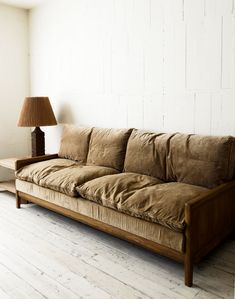 a couch sitting on top of a wooden floor next to a lamp