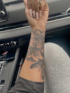 a woman's arm with flowers on it and a butterfly tattooed on the wrist