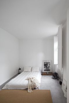 a bed sitting in the middle of a bedroom next to a doorway and window on top of a carpeted floor