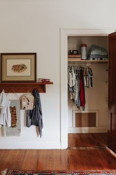 an open closet with clothes hanging on the wall and a rug in front of it