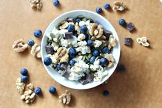 a white bowl filled with blueberries and nuts on top of a wooden table next to chocolate chips