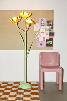 a pink chair sitting next to a yellow flower in a vase on top of a table