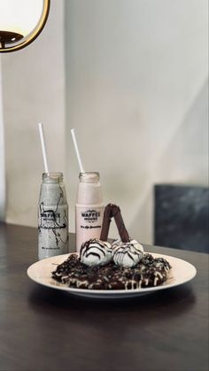 two drinks are sitting on a plate next to some chocolate covered marshmallows