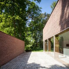 a brick walkway between two buildings with glass doors on each side and trees in the background