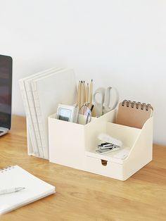 a desk with a laptop, pen and paper holder on it next to a notebook