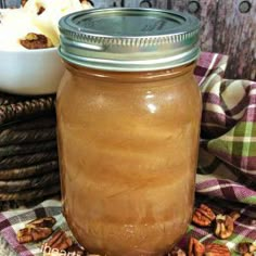 a glass jar filled with liquid sitting on top of a table next to some nuts