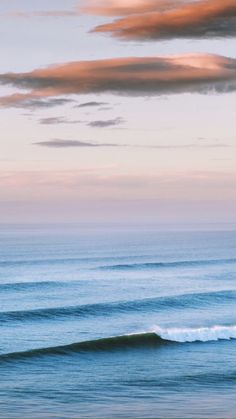 two surfers are riding the waves on their surfboards in the ocean at sunset