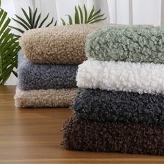 four towels stacked on top of each other in front of a potted palm tree