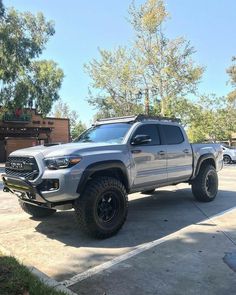 a silver toyota truck parked in a parking lot next to other cars and trees on a sunny day