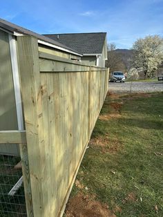 a wooden fence next to a house with a car parked in the background