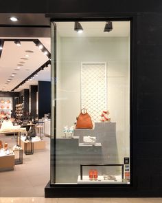 the inside of a shoe store with shoes and bags on display behind glass doors that are open