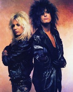 two women standing next to each other in black leather outfits and hair with spikes on their head