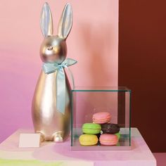 a metal bunny sitting next to some macaroni and cheese pastries on a table