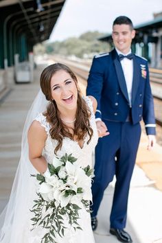 a bride and groom are standing on the train tracks at their wedding day, posing for a photo