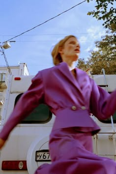 a woman in a purple dress is standing next to a white truck