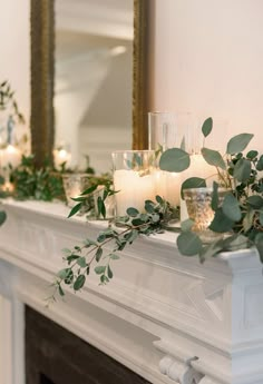 candles and greenery are arranged on the mantle