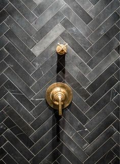 a black and gold tiled shower stall with a brass faucet in the middle