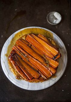 a white plate topped with sliced carrots on top of a table