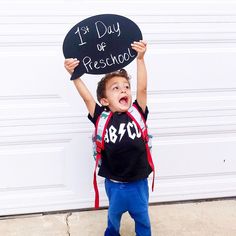 a young boy holding up a chalkboard with the words 1 st day of preschool written on it