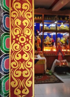 an ornate red and yellow pole in front of a store filled with colorful items on display