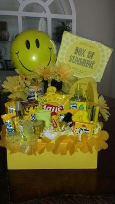 a yellow box filled with lots of goodies and a smiley face balloon in it