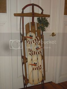 a wooden sled with two snowmen on it's sides hanging from the door