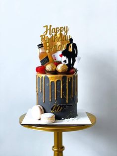 a black and gold birthday cake sitting on top of a table